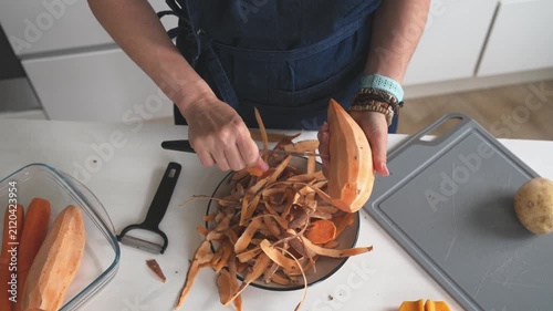 Woman Peeling A Raw Sweet Potato In A Closeup Top-Down View
