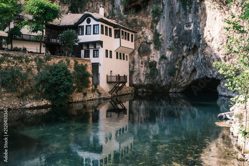 Bild auf Leinwand view of the historic Blagaj Tekija Sufi monastery nestled against a massive vertical rock cliff beside the crystal-clear Buna river spring in Bosnia