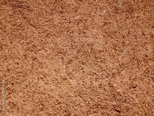 фотографія Traditional earthen wall texture with red clay and straw, Rough red clay earthen