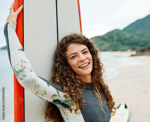 Canvas Print Portrait of a young woman surfing at the beach, holding surfboard, ocean waves,