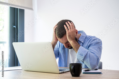 Obraz na plátně Man covering his head with hands, feeling intense frustration and burnout while