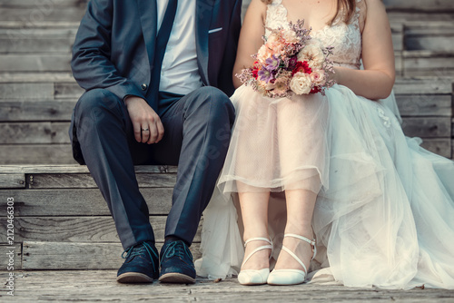 Bride and groom sitting on wooden stairs with bouquet