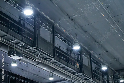 The black plumbing system above the ceiling in a large area includes lighting fixtures, air conditioning ducting, electrical wiring, and signal cabling.