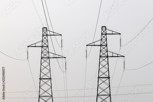 Close-up of two high voltage power pylons against a plain light sky.