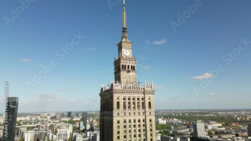 Aerial view of Warsaw’s Palace of Culture and Science rising above the city, with clear blue sky, urban roads and iconic Polish capital architecture.