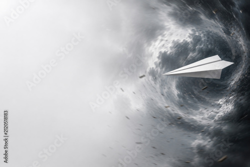 Paper airplane flies through a powerful dark vortex. Space for text.