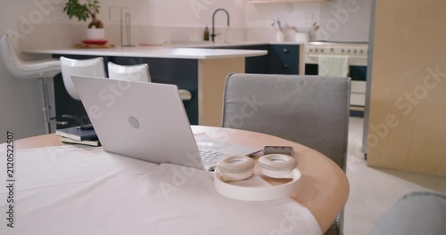Camera is moving closer, revealing laptop and headphones on round table to show smartphone
