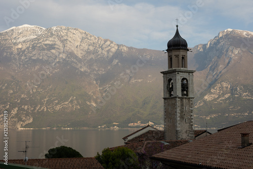 Historic church bell tower overlooking Lake Garda and mountain landscape in Italy
