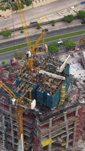 Timelapse of a skyscraper construction site in Dubai with tower cranes rotating above the workers building the modern concrete high rise.