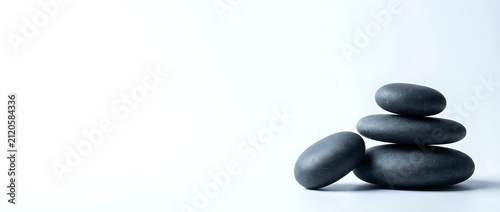 Stacked smooth dark stones on white background, symbolizing balance, wellness, and meditation for spa, relaxation, and mindfulness design projects.