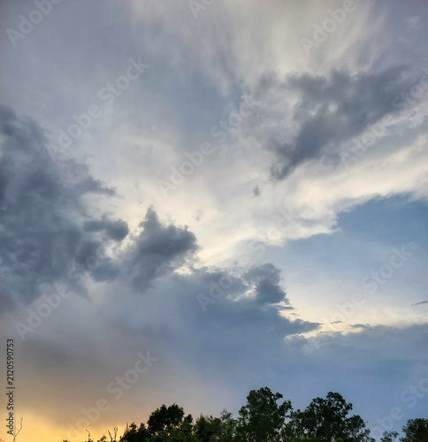 Sunset scenery, dark clouds in blue sky background, silhouette of trees, nature photography, dramatic weather conditions wallpaper