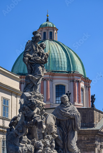 Statues of Madonna and Saint Bernard at Charles bridge in Prague. Church of St. Francis in background
