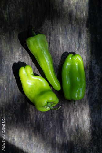 fresh green bell peppers on dark rustic wooden background, top view