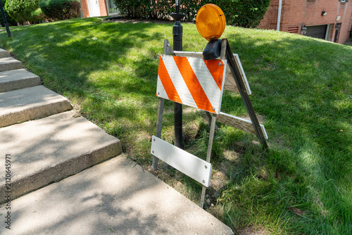 Fotografie Road safety barricade with warning light beside a sidewalk and steps