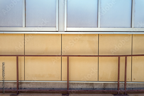 Obraz na płótnie A two-toned paneled exterior wall and a metal handrail running in parallel