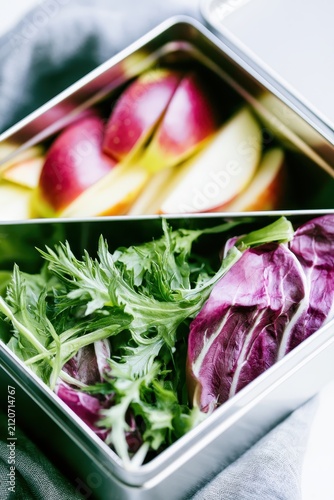 Metal lunch box with fresh salad and apples. Healthy food container for school or work.