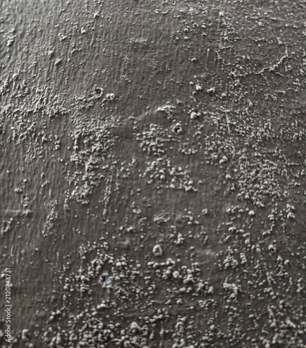 Dark grey painted textured wall background with bumpy rough surface finish.