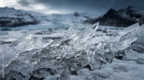 Close-up of jagged ice formations on a frozen landscape with mountains in the background.