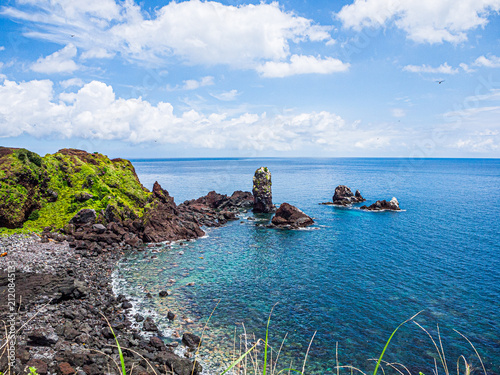JEJU, SOUTH KOREA - JULY 30, 2026: Volcanic sea stacks and rugged basalt coastline at Seopjikoji on Jeju Island under a dramatic summer sky.