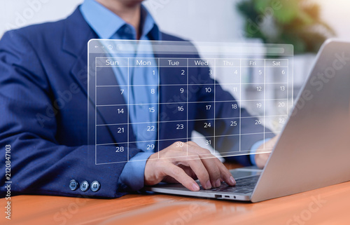 Business professional using digital calendar scheduling interface on laptop for appointment planning, time management, project organization, online booking, productivity, workflow optimization.