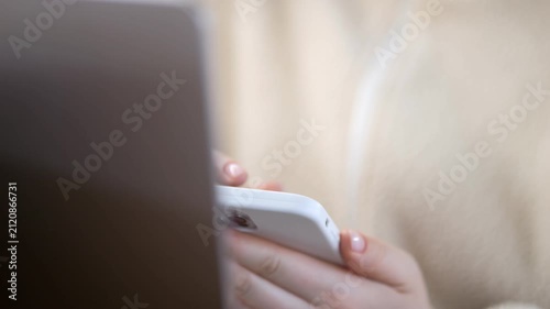Close-up of hands using smartphone and laptop. Person focused on digital devices. Suitable for tech, multitasking, or modern work concepts