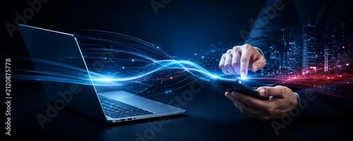 Businessman connecting smartphone to laptop with glowing data streams, symbolizing digital transformation and network connectivity.