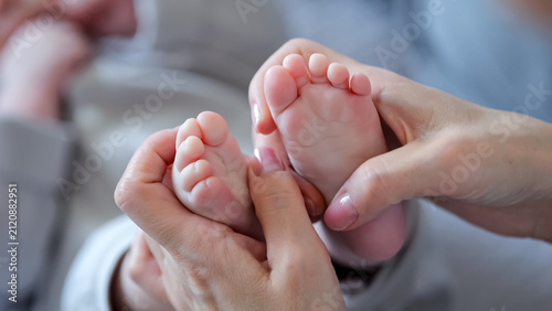 Fotografie Mother's hands gently holding a newborn baby's tiny feet, symbolizing the intima