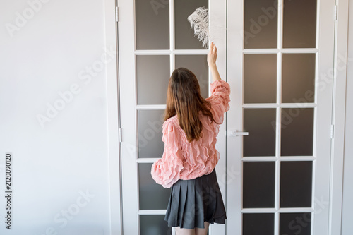 Cuadro en lienzo Young woman seen from behind dusting a white french door with frosted glass pane