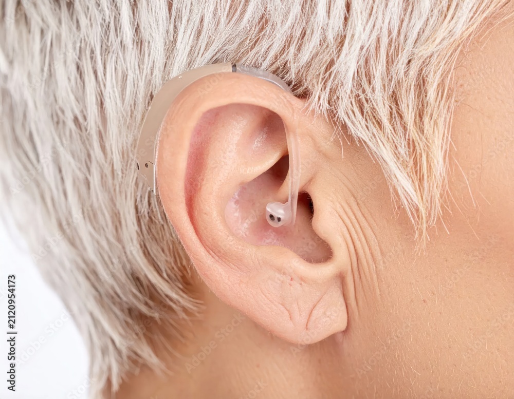 Fototapeta premium Modern hearing aid worn in human ear close-up.