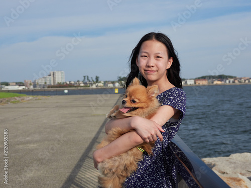 夏の海の海岸で可愛いポメラニアンの子犬を連れて散歩する十代の女の子の子供の姿