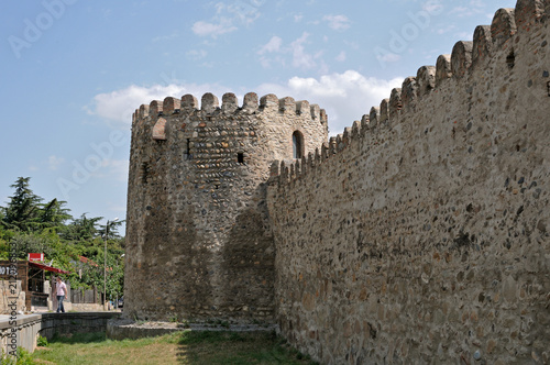 Fotografie Ancient stone fortress wall and round defensive tower in Mtskheta under sunny sky