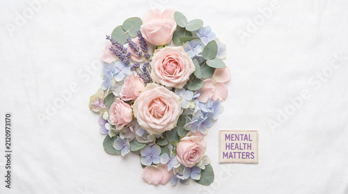 Mental Health Awareness Concept - Human Head Silhouette Made of Blooming Flowers and Green Leaves on White Background, Minimalist Flat Lay Style