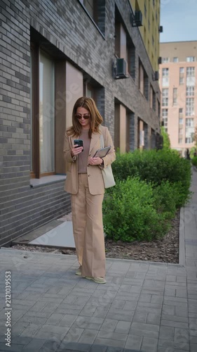 Real estate agent on smartphone by building
