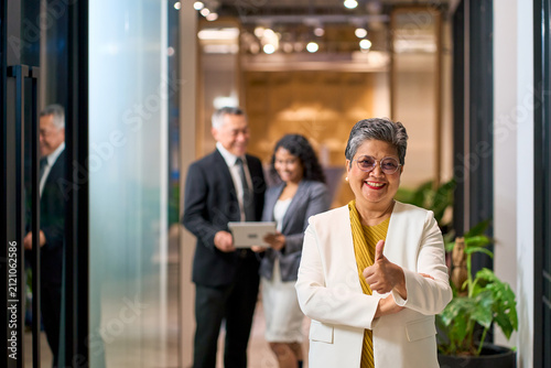 Successful Senior Asian Businesswoman Giving Thumbs Up in Office with Diverse Professional Team, Leadership and Corporate Achievement Concept.