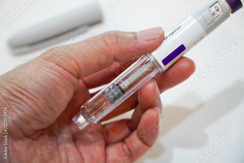 man's hand is using a weight-loss injection pen. Concept of losing weight with the drug