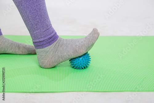 Cuadro en lienzo A close-up of a woman massaging her feet with a massage ball on a yoga mat, practicing fitness and relieving discomfort