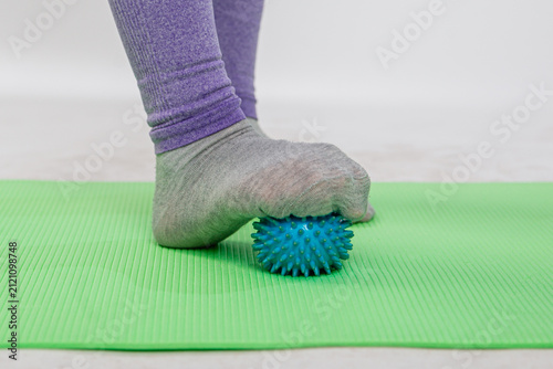 Cuadro en lienzo A close-up of a woman massaging her feet with a massage ball on a yoga mat, practicing fitness and relieving discomfort