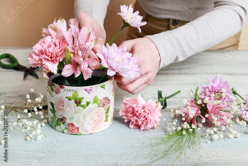 Florist at work: woman shows how to make flower box with alstroemerias, chrysanthemums and carnations in cute pink color, suitable for wedding or birthday present. Step by step, tutorial.