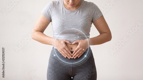 A woman placing her hands on her stomach, symbolizing wellness and connection to health and emotions.