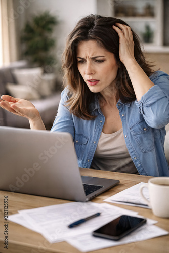 She looks confused at the computer screen. Documents lay on desk. AI generated
