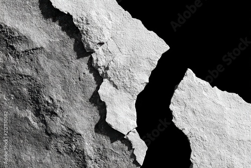 Jagged rock formation with sharp crack against pitch black background symbolizing struggle or broken foundation in high contrast monochrome photography