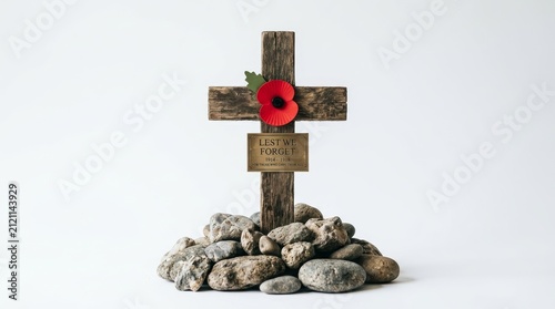 A wooden remembrance cross featuring a red poppy and Lest We Forget plaque on rocks