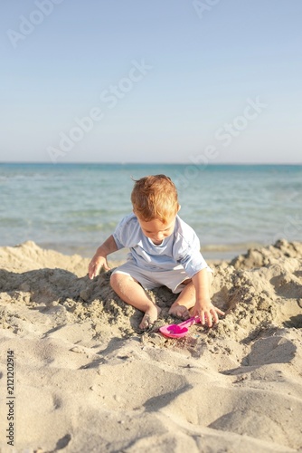 little boy playing in the sand on the beach