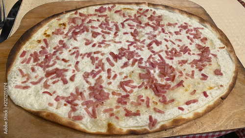 Freshly baked Alsatian Flammekueche flatbread pizza with cream and bacon lardons
