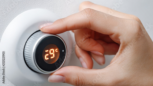Hand adjusting the heating temperature dial in a cozy home setting for optimal comfort and warmth