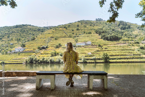 Frau auf Bank mit Blick auf Weinberge und Douro-Fluss im Douro-Tal, Portugal