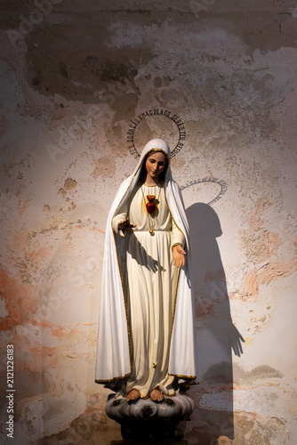 Statue der Jungfrau Maria an einer alten Steinmauer – christlicher Glaube, Religion und religiöse Symbolik