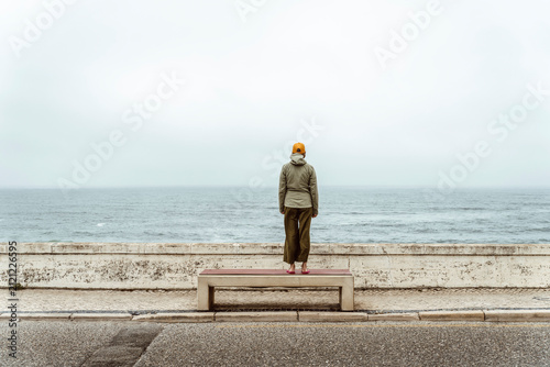 Frau steht am Meer auf einer Bank – Auszeit, Nachdenken und Ruhe an der Küste