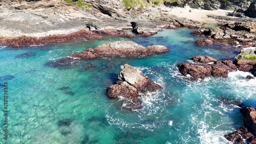 Fototapeta premium Aerial View of Turquoise Ocean Waves Crashing Against Rocky Coastline