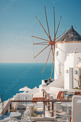 Whitewashed cycladic architecture and an iconic windmill standing against the blue sky and sea
